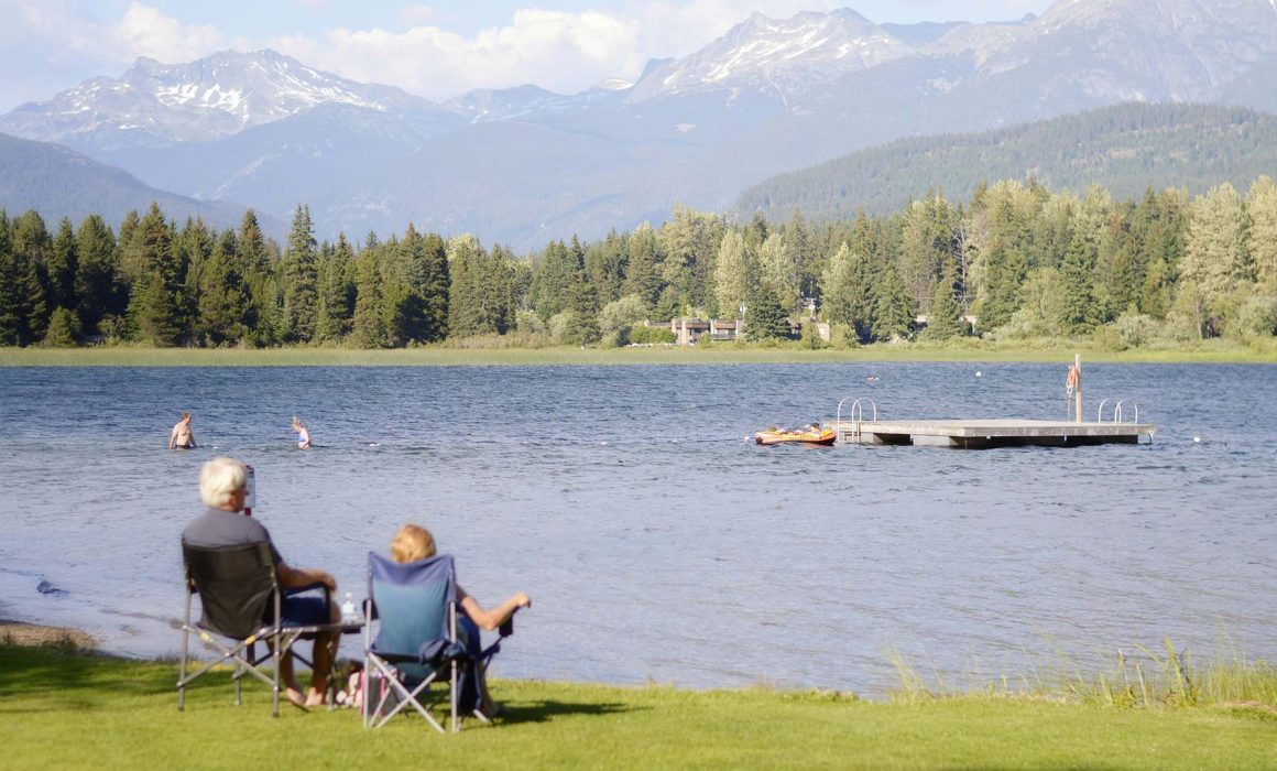 retired couple sitting on park bench feeding the ducks