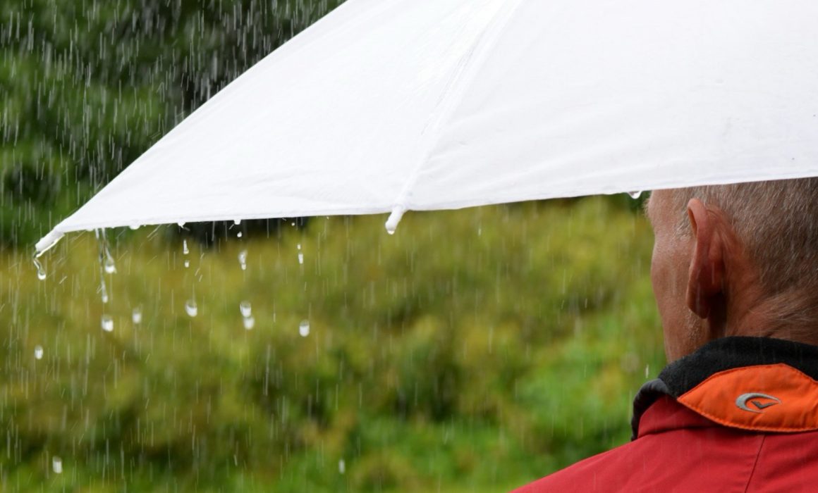 man standing in the rain with an umbrella thinking about insurance
